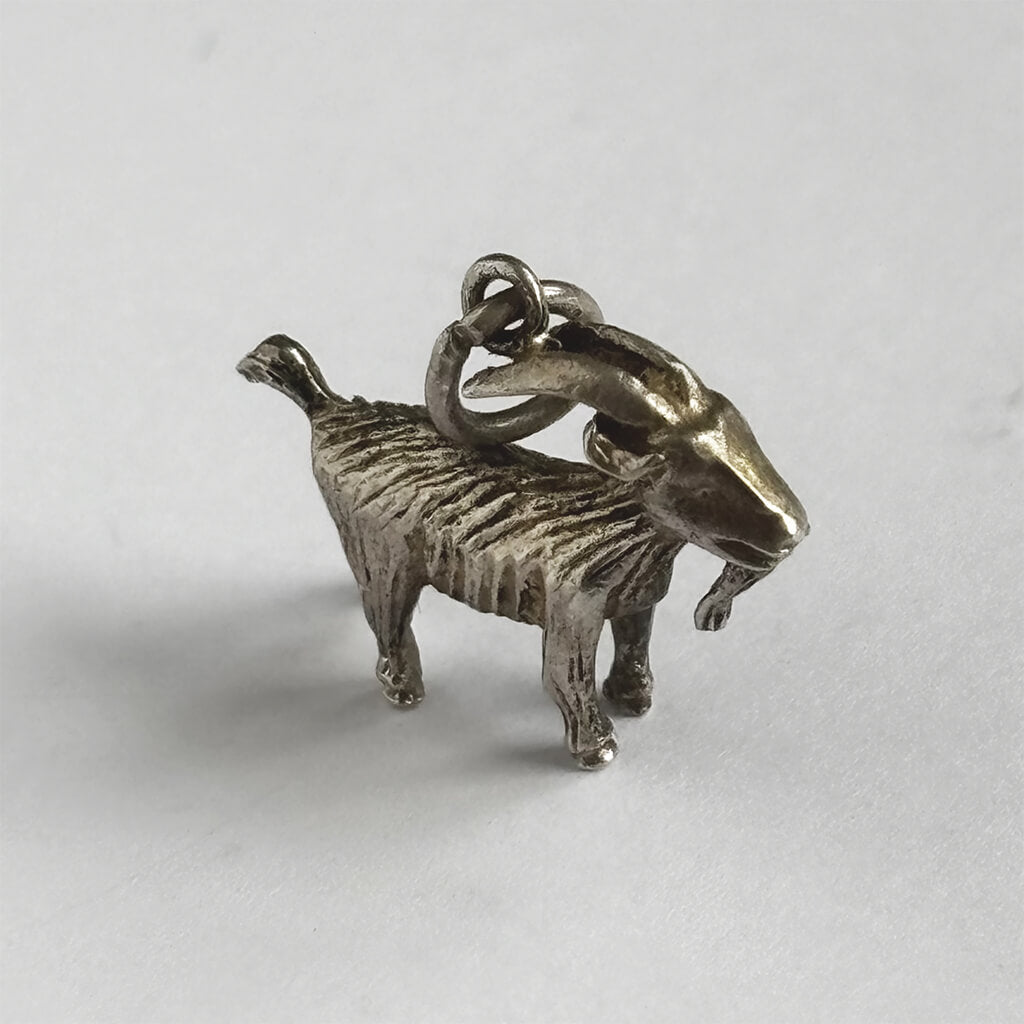 Silver goat charm on a white background