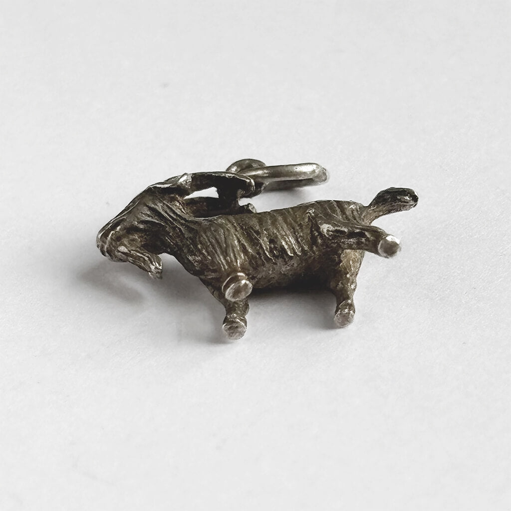 Silver vintage goat charm on a white background