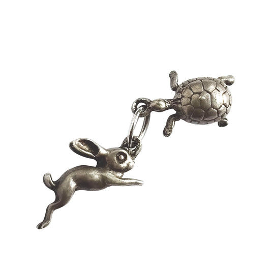 A vintage silver hare and tortoise charm on a white background.