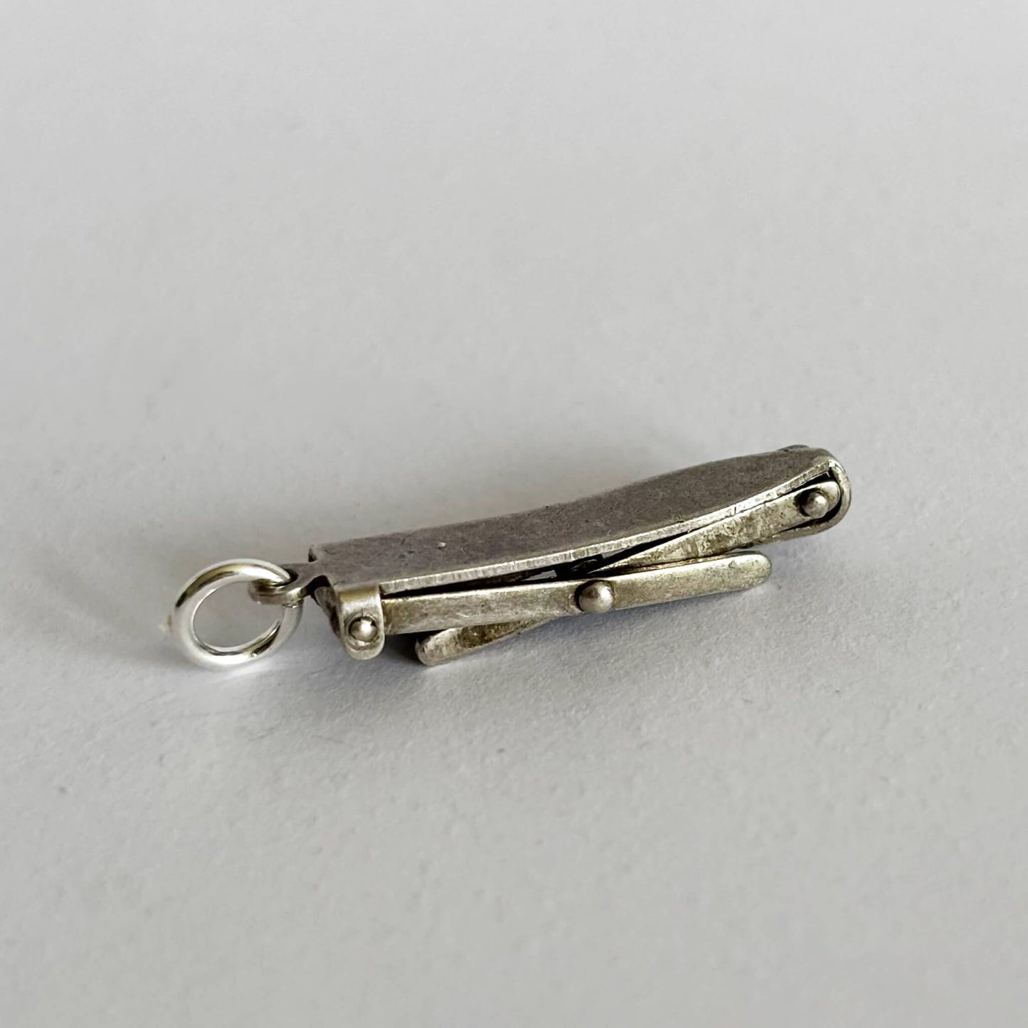 Silver ironing board charm on a light gray background