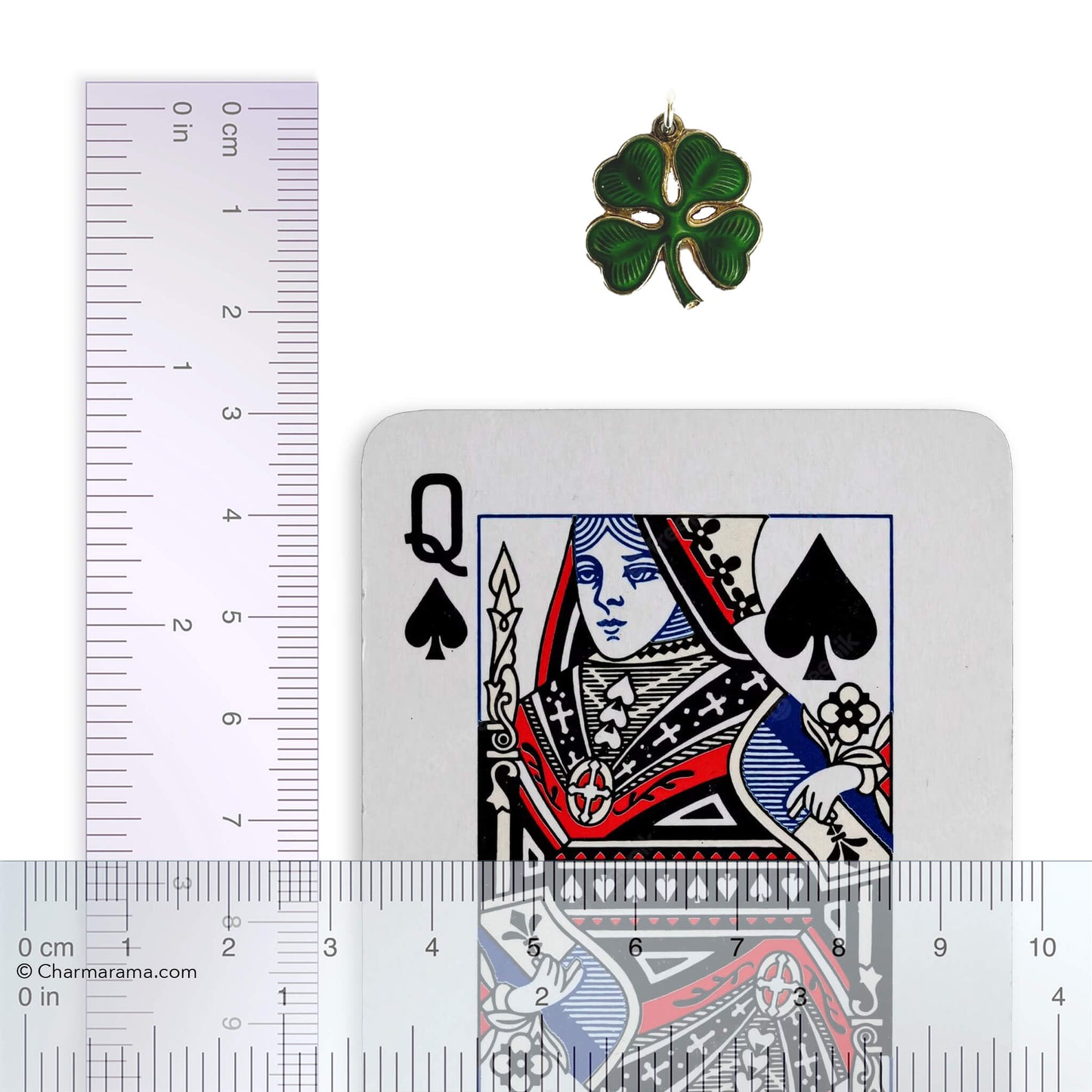 Green four-leaf clover charm with playing card and ruler for scale on a white background