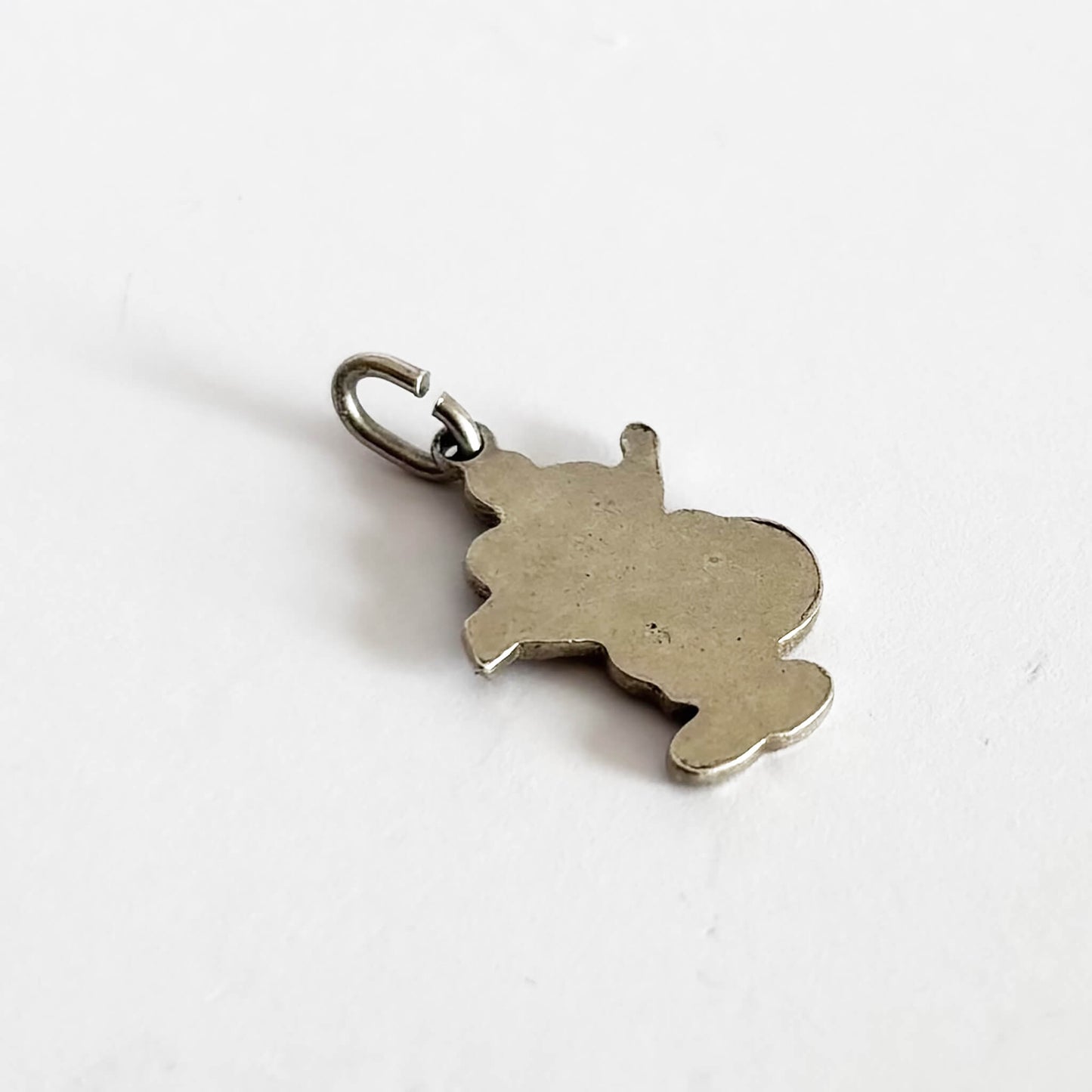 Back of a silver charm on a white background
