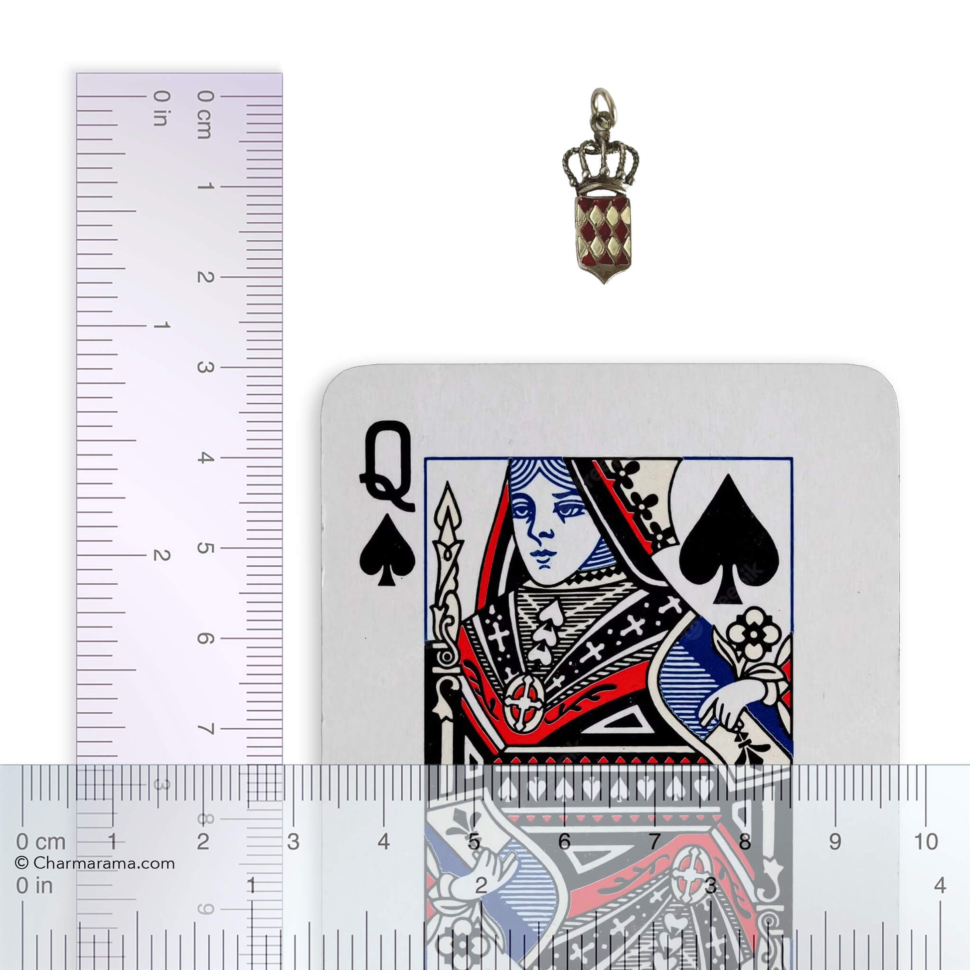 Silver and enamel Monaco flag and crown charm with playing card and ruler for scale on a white background