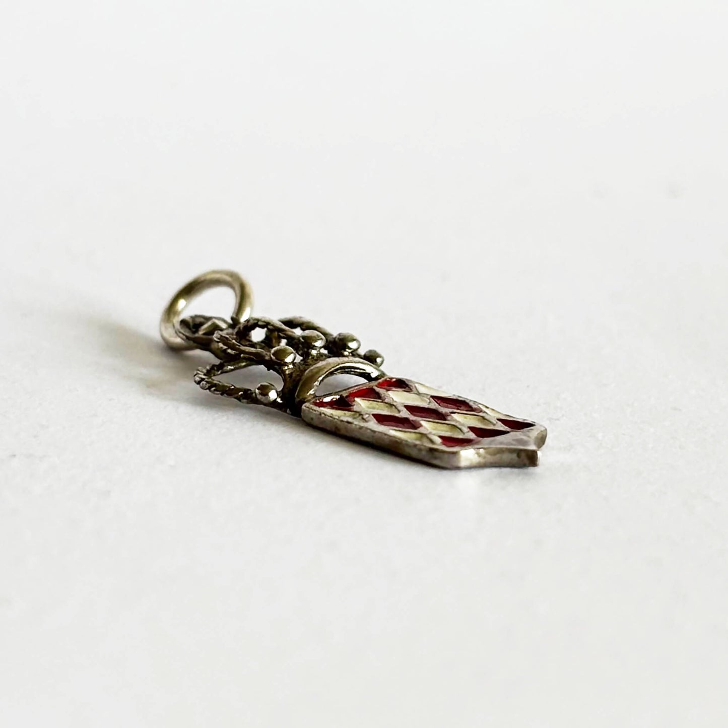 Silver and enamel Monaco flag and crown charm viewed from side on a white background
