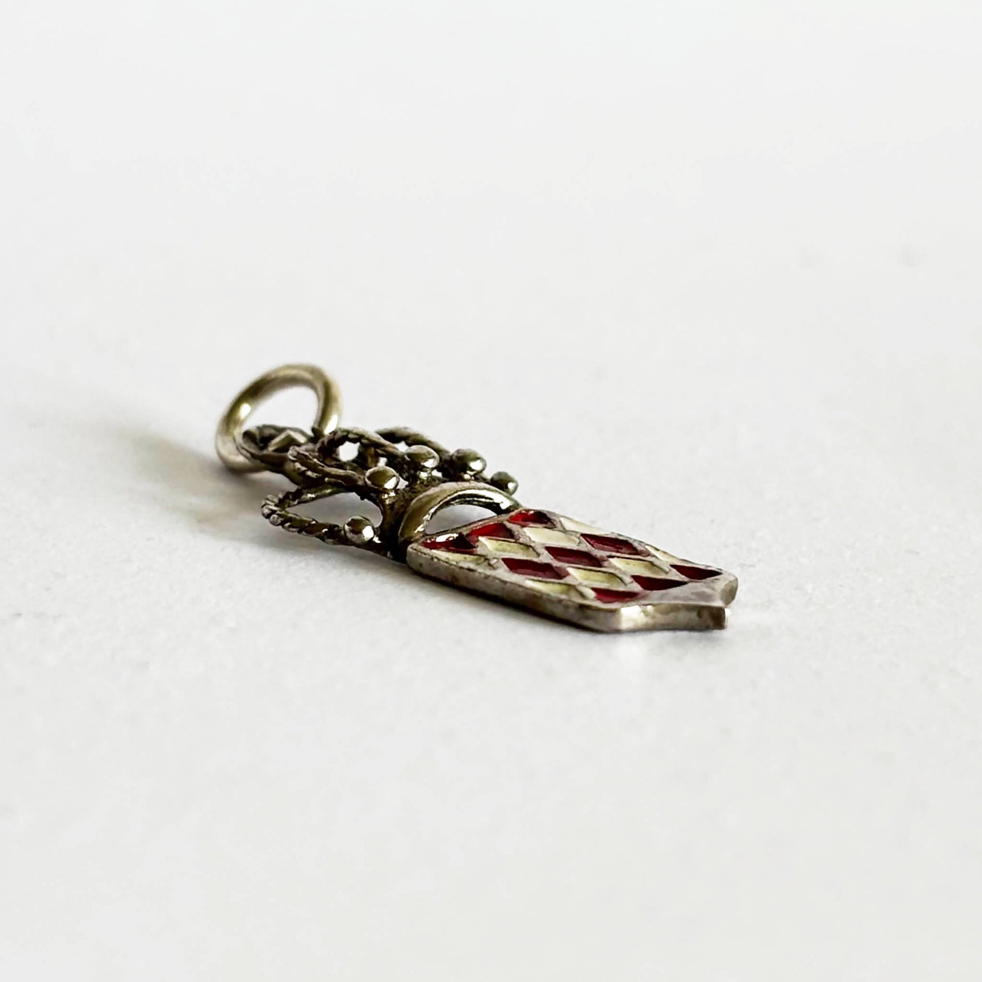 Silver and enamel Monaco flag and crown charm viewed from side on a white background