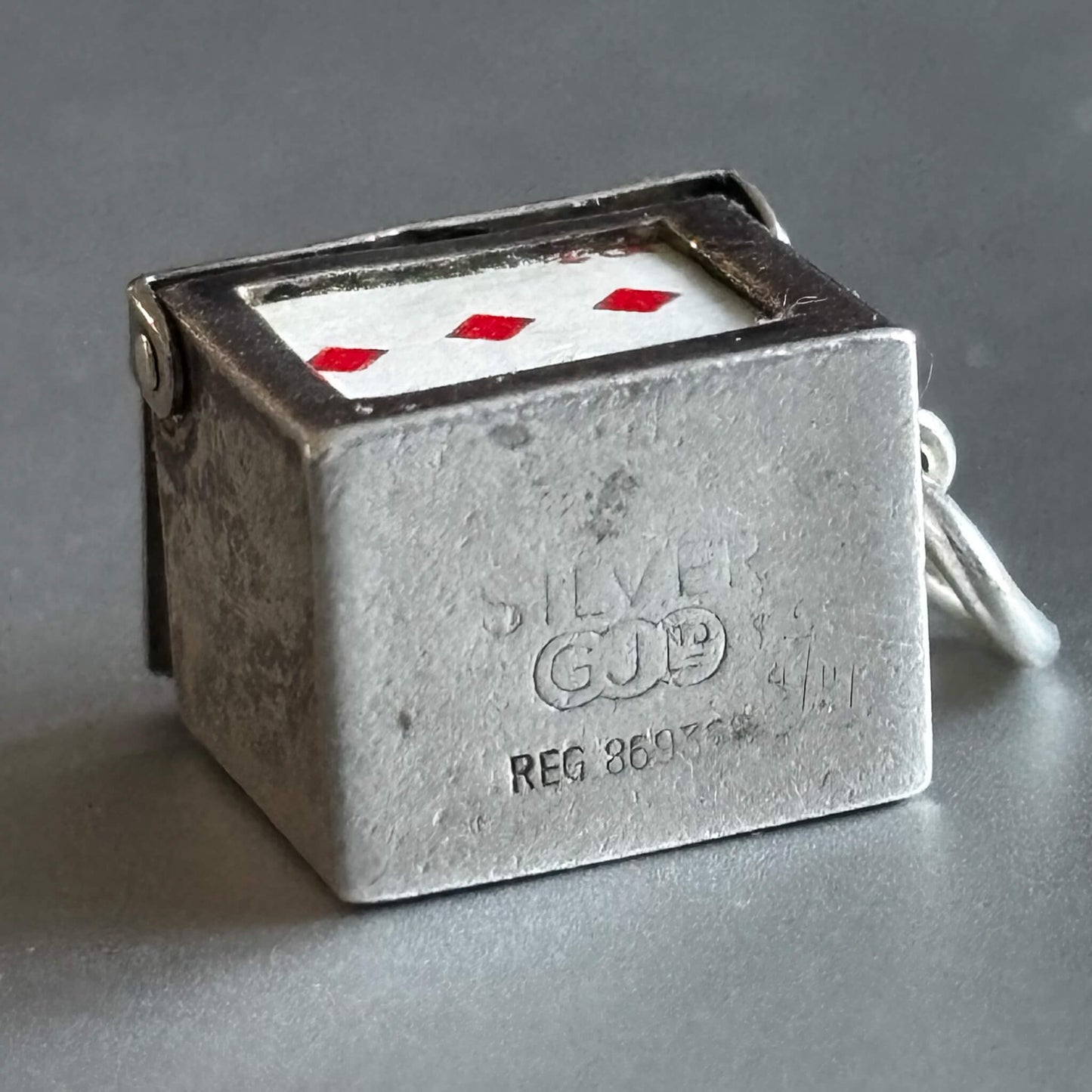 Vintage silver box of playing cards charm on a grey background