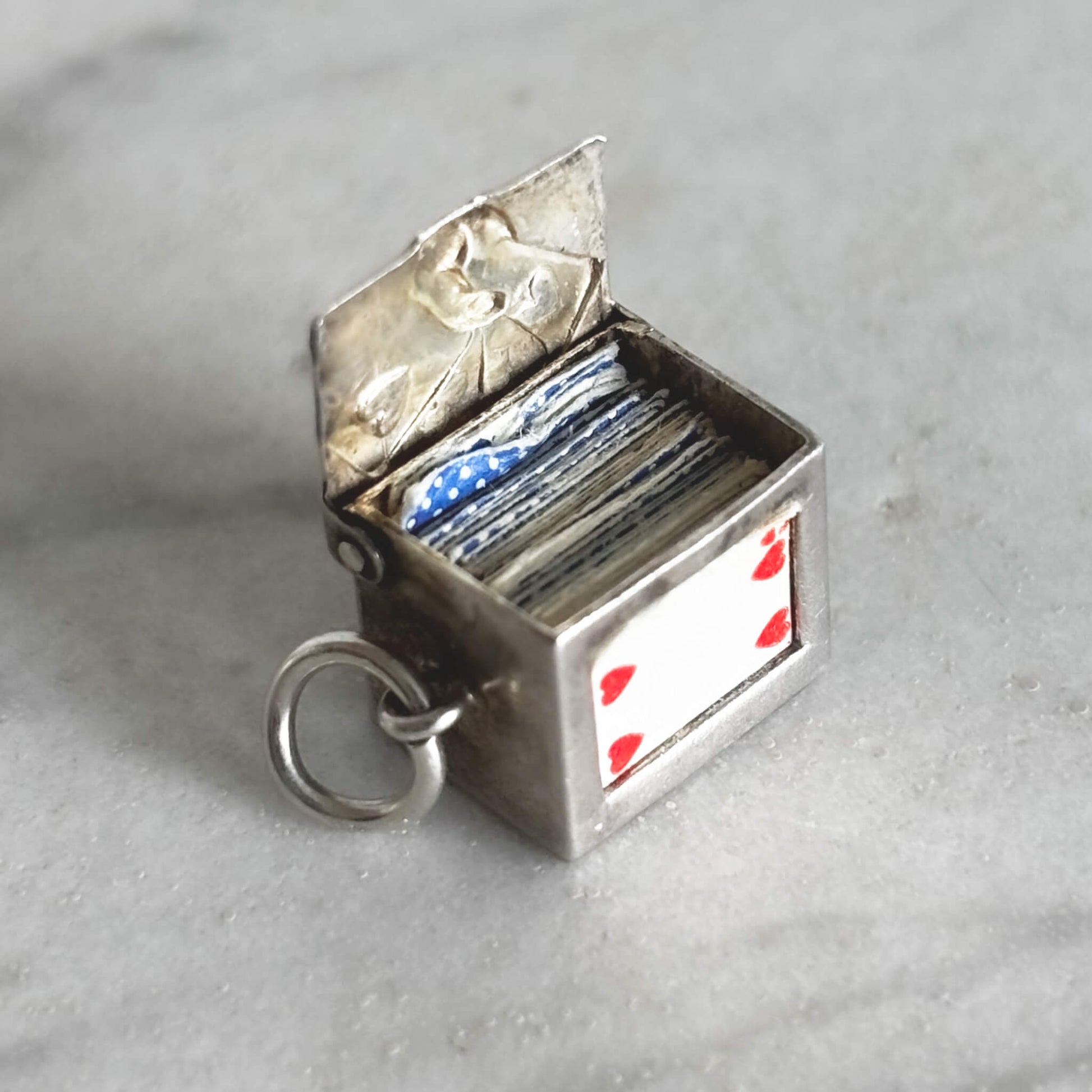 Vintage silver box of playing cards charm on a grey background