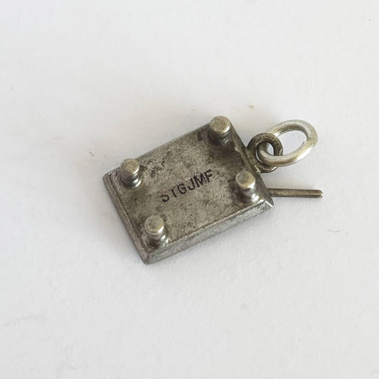 Underside of silver pool table charm on a white background.