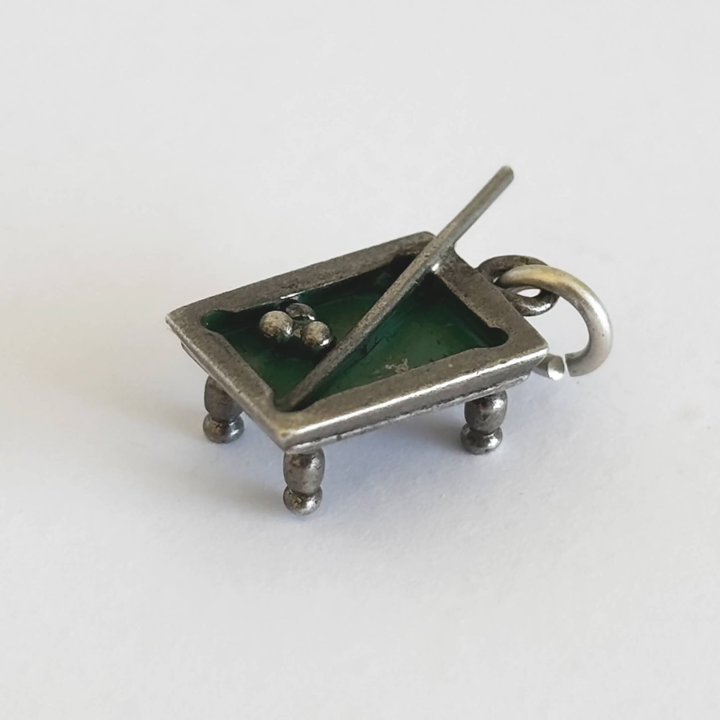 Silver and green enamel pool table charm with cue and three balls on a white background.