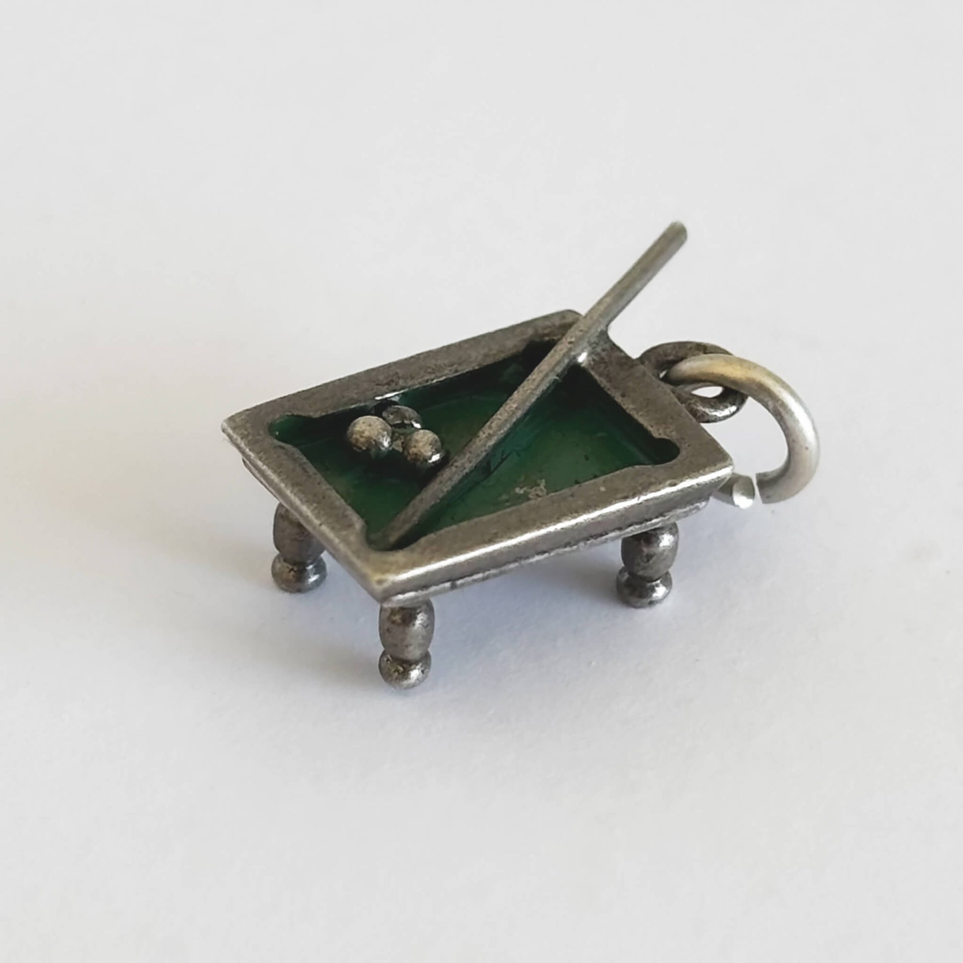 Silver and green enamel pool table charm with cue and three balls on a white background.