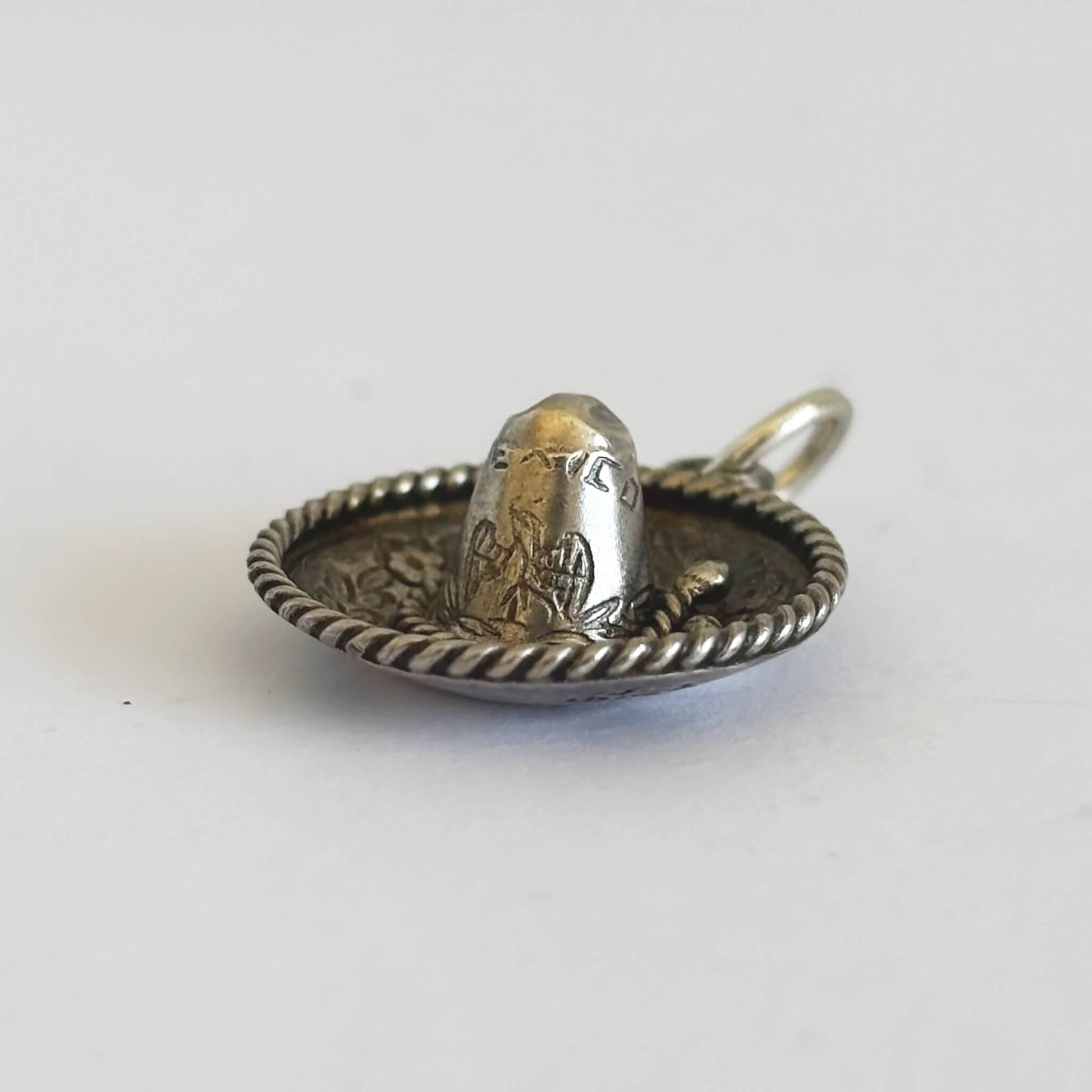 Silver sombrero and hat charm on a white background