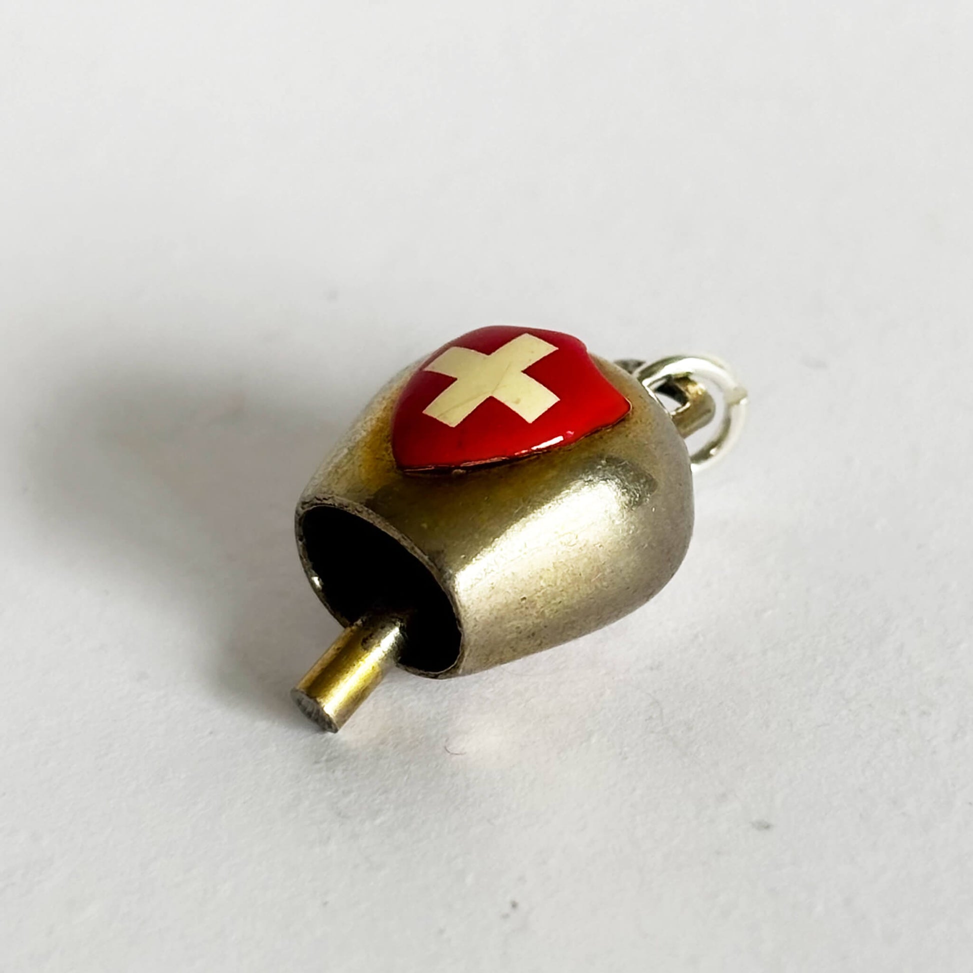 Small cow bell charm with a Swiss flag on a white background
