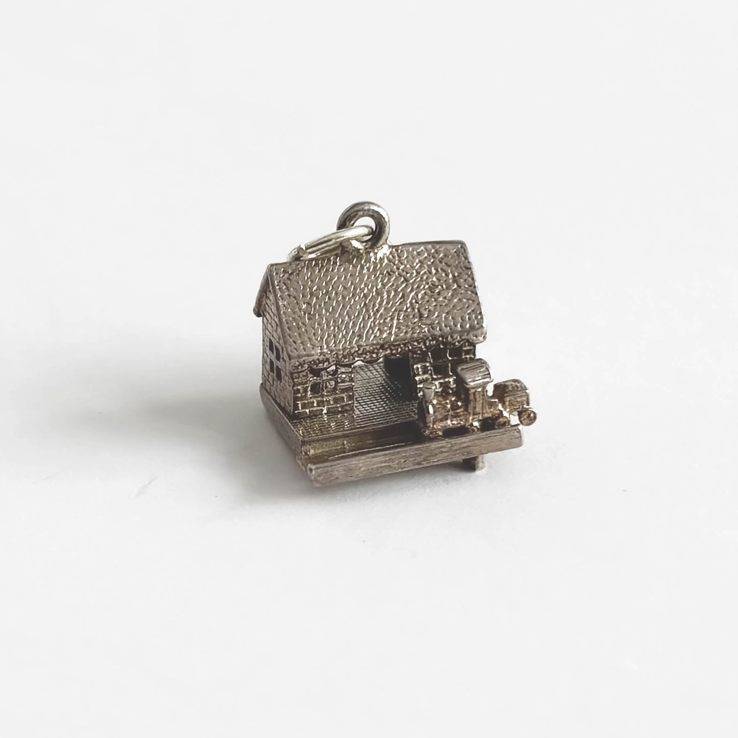 A vintage silver train in station charm on a light grey background