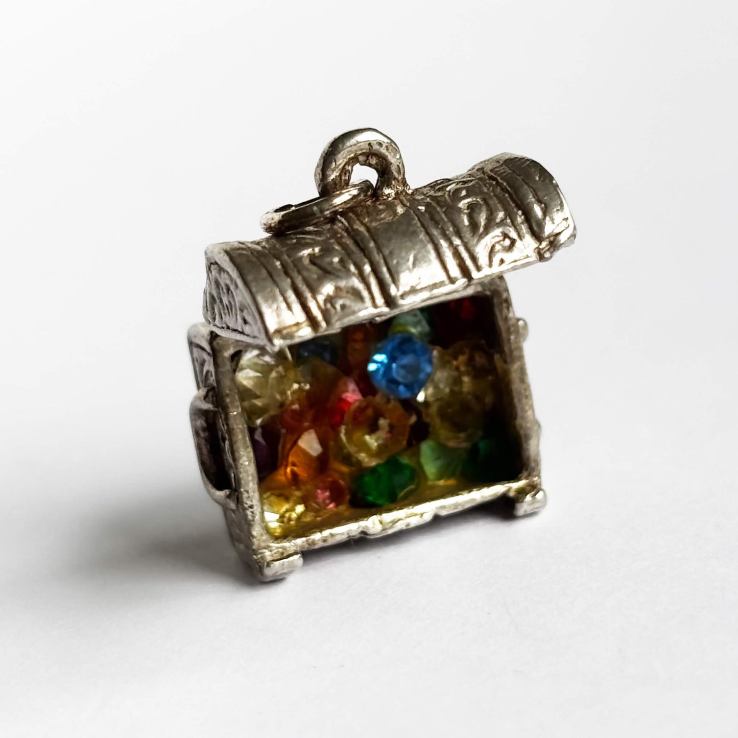 Vintage silver treasure chest charm shown open displaying crystals inside on a white background.