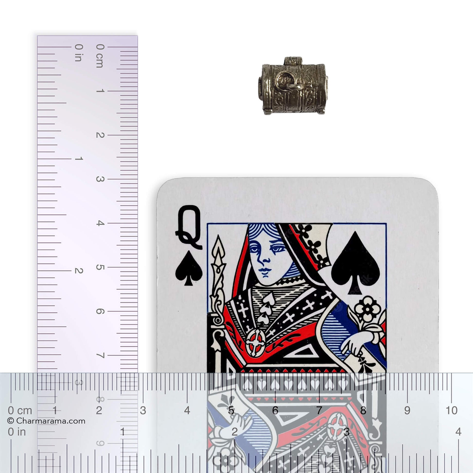 Vintage silver treasure chest charm with playing card and ruler for scale on a white background.