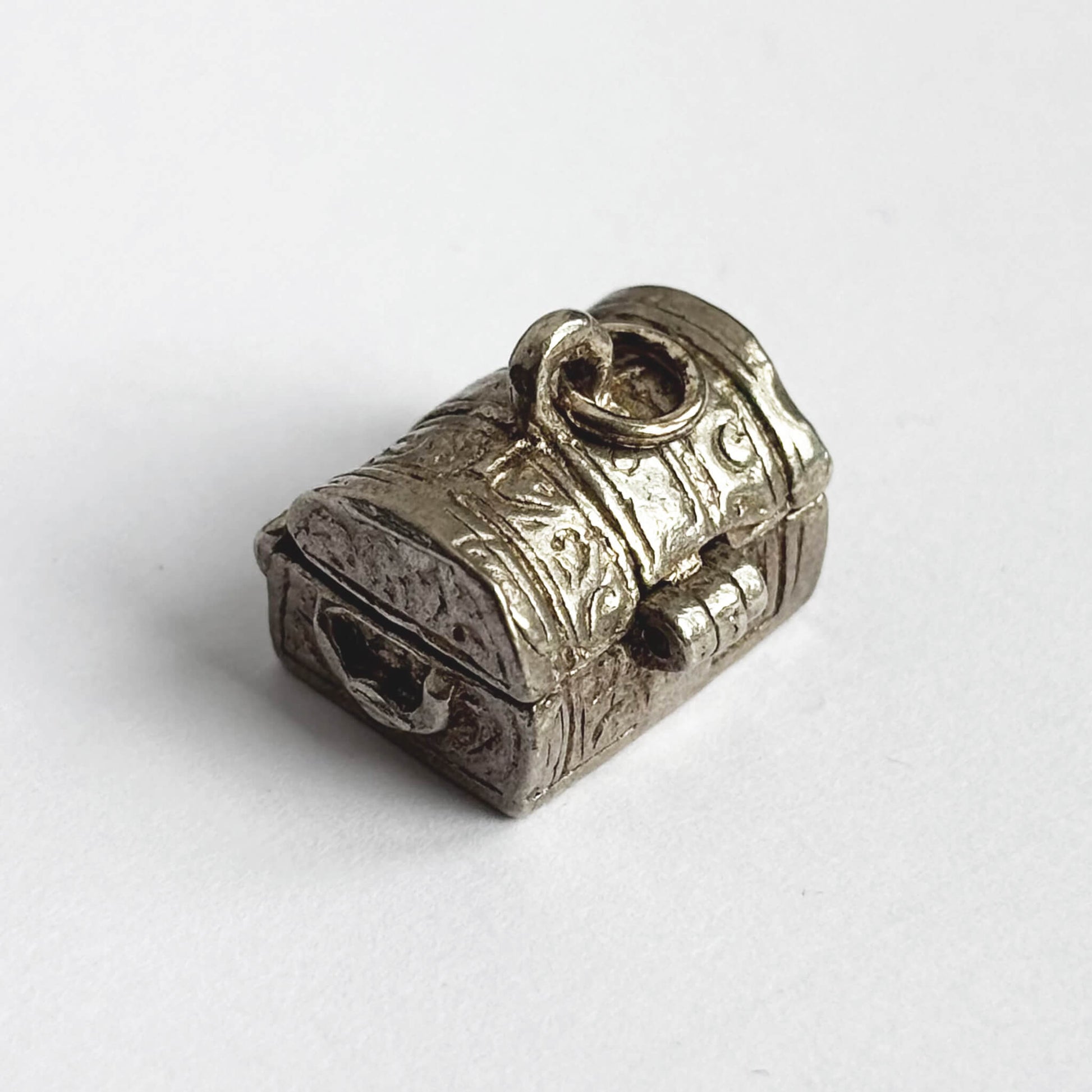 Vintage silver treasure chest charm shown in closed position on a white background.