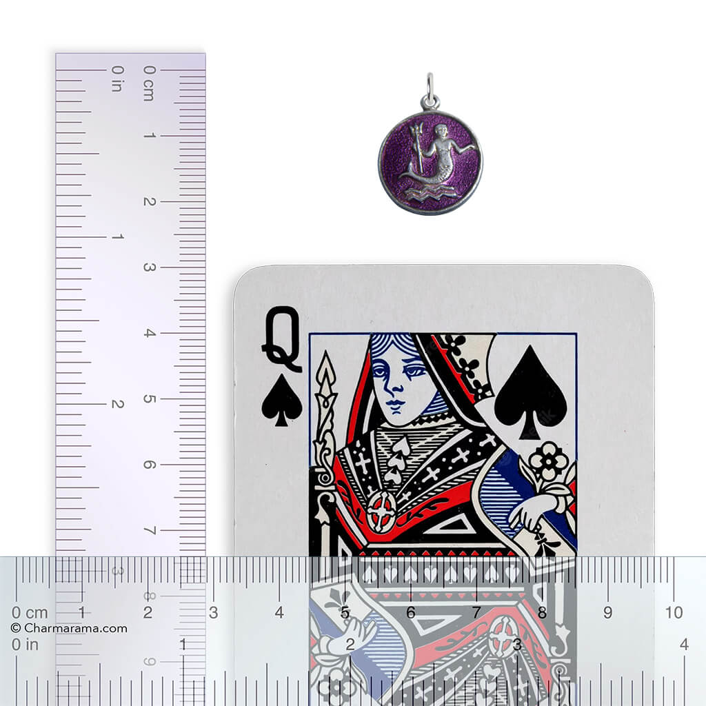 Pendant next to a playing card with a ruler for scale