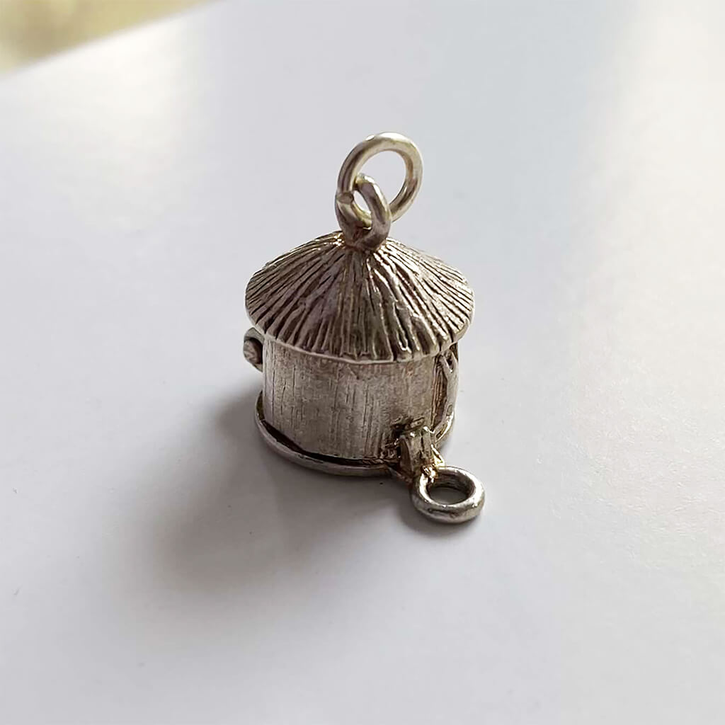Mud hut opening to man in cauldron silver charm cannibal pendant