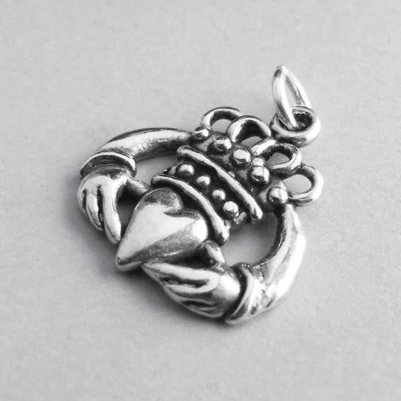 silver Irish Claddagh hands heart crown symbol pendant on grey background