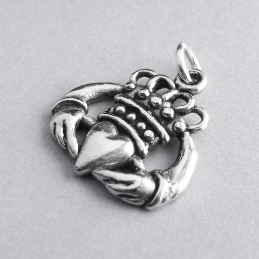 silver Irish Claddagh hands heart crown symbol pendant on grey background