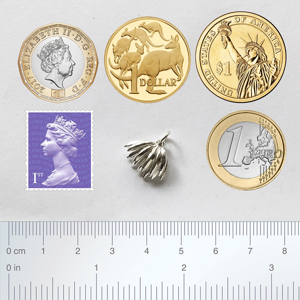 A hand of bananas with coins and ruler for scale