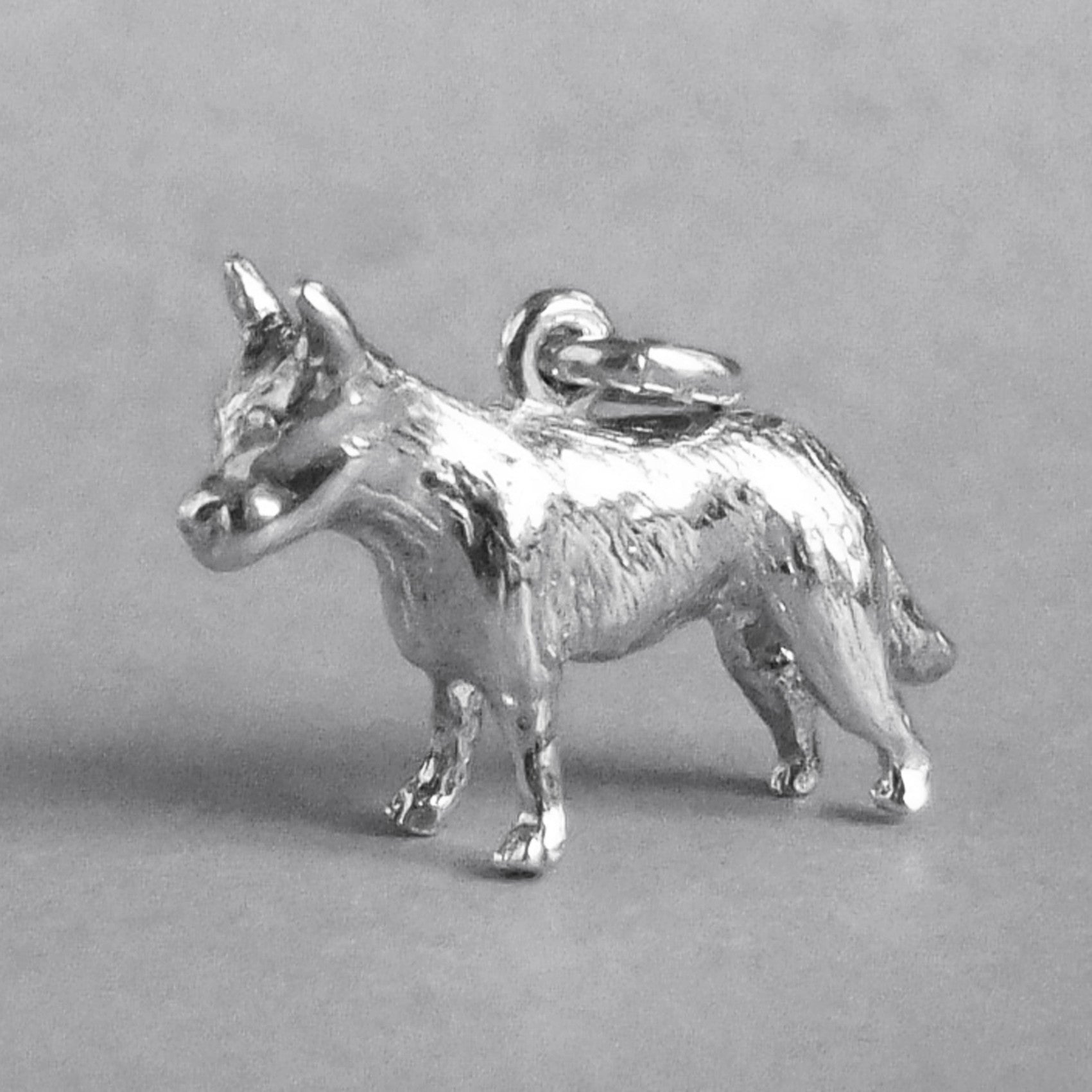 Silver blue heeler cattle dog charm seen from side on a grey background.