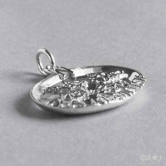 Side view of sterling silver Falkland Islands charm on a grey background