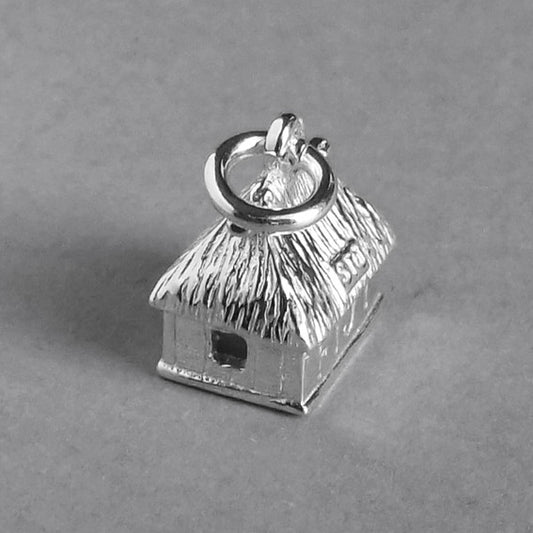 Sterling silver Fijian bure charm on a grey background