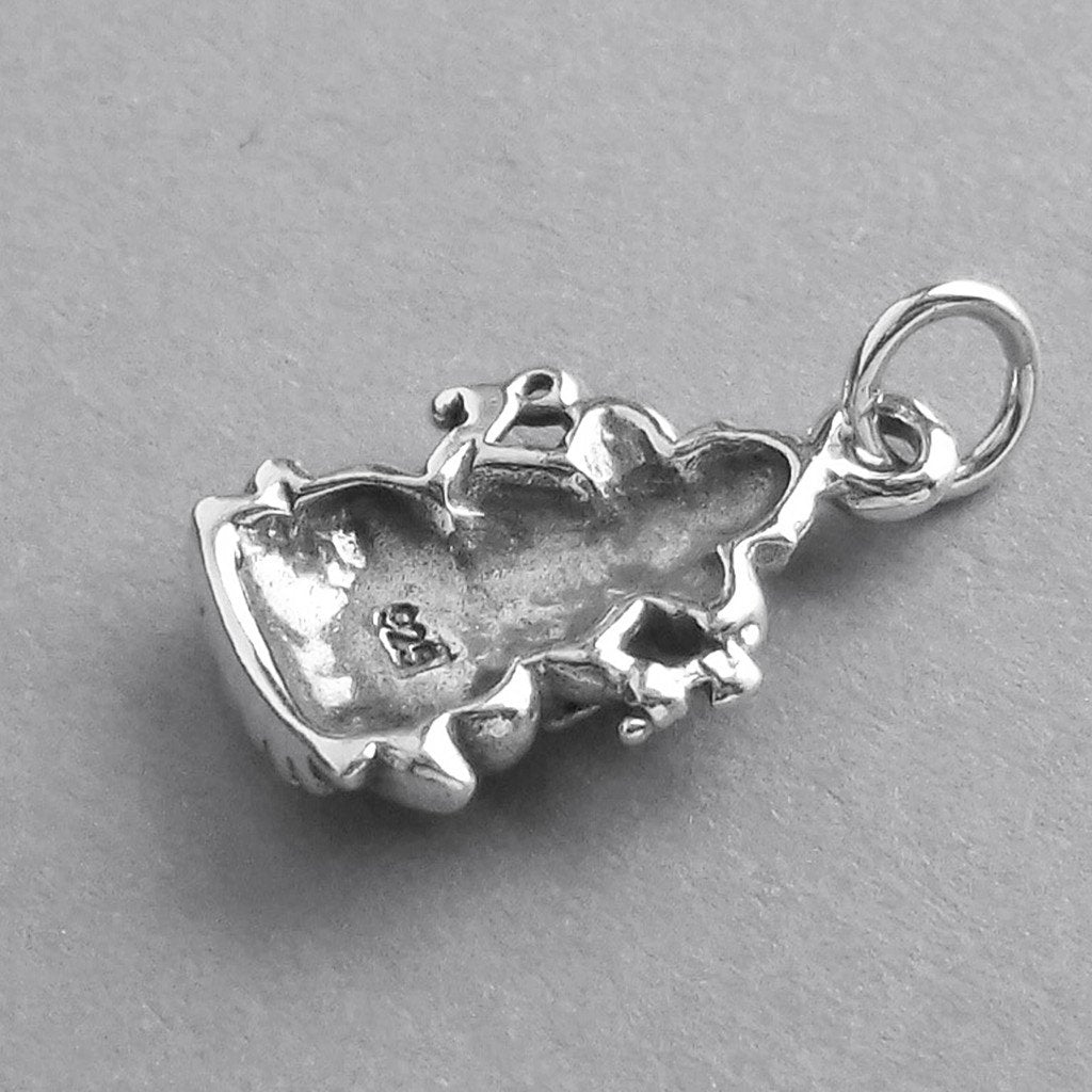 Reverse side of a sterling silver Ganesh charm on a grey background