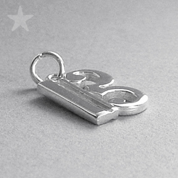 silver alto clef charm lying on grey surface