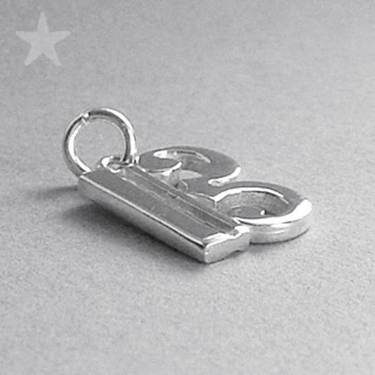 silver alto clef charm lying on grey surface