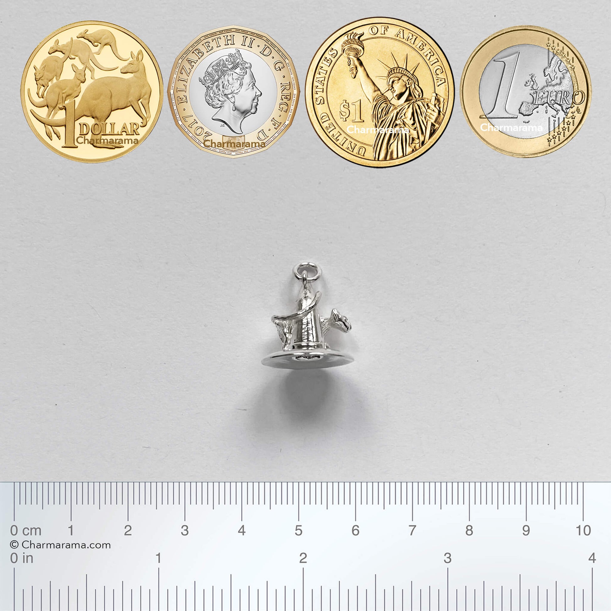 silver cat on witch hat charm with coins and ruler for scale on a grey background