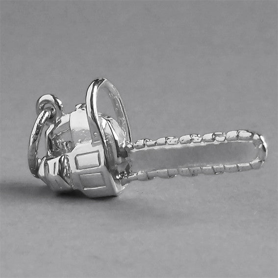 silver chainsaw charm on a grey background