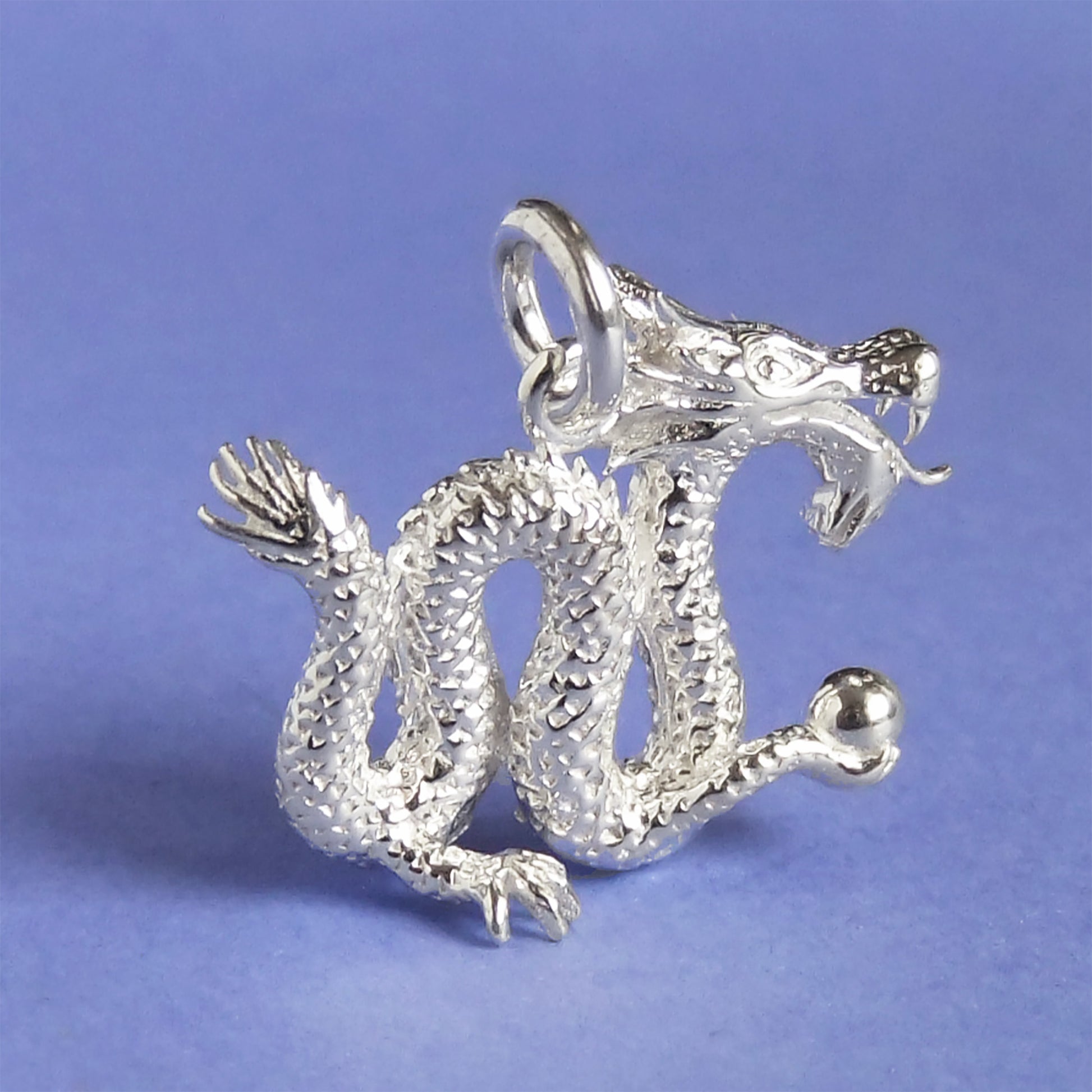 silver Chinese dragon charm on a purple background