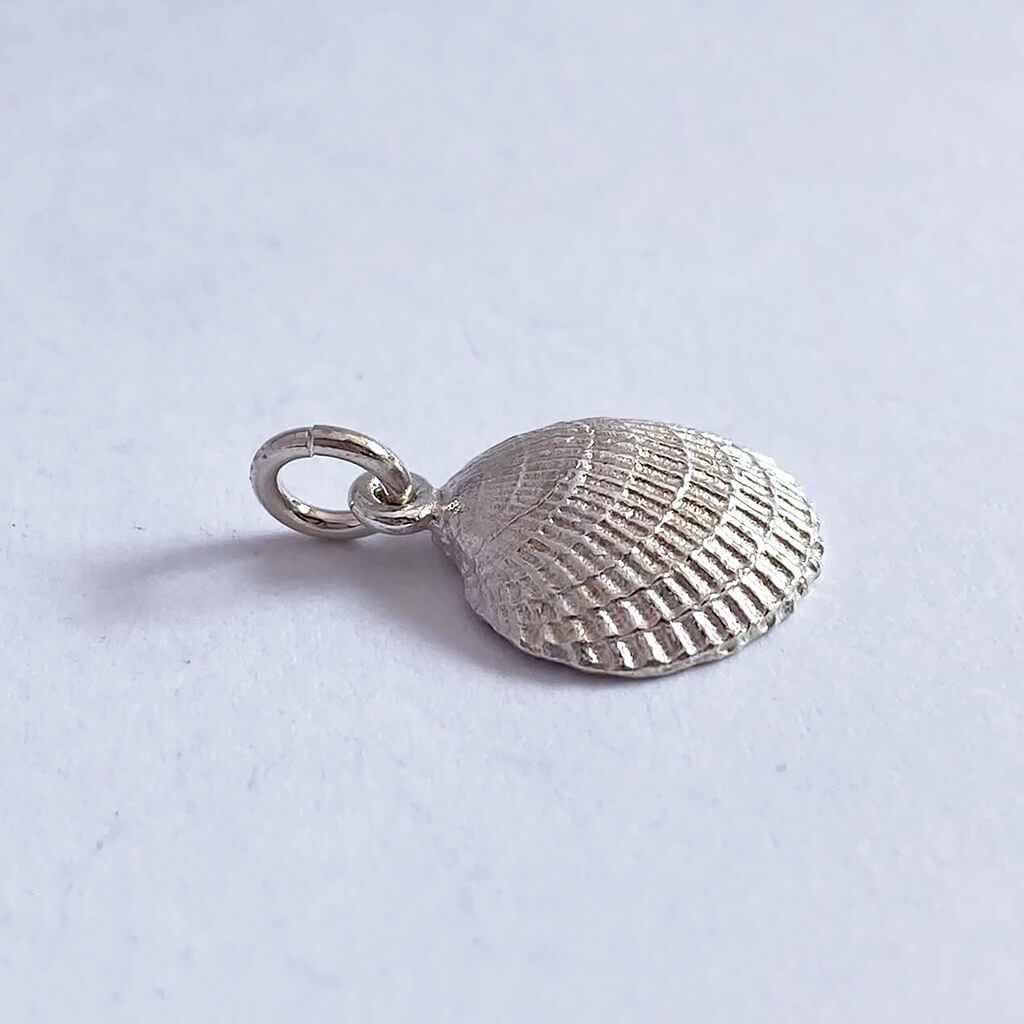Sterling silver cockle shell charm on grey background
