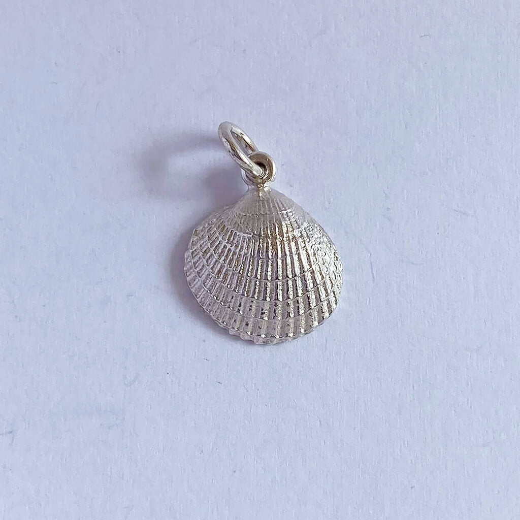 Sterling silver cockle shell charm on grey background