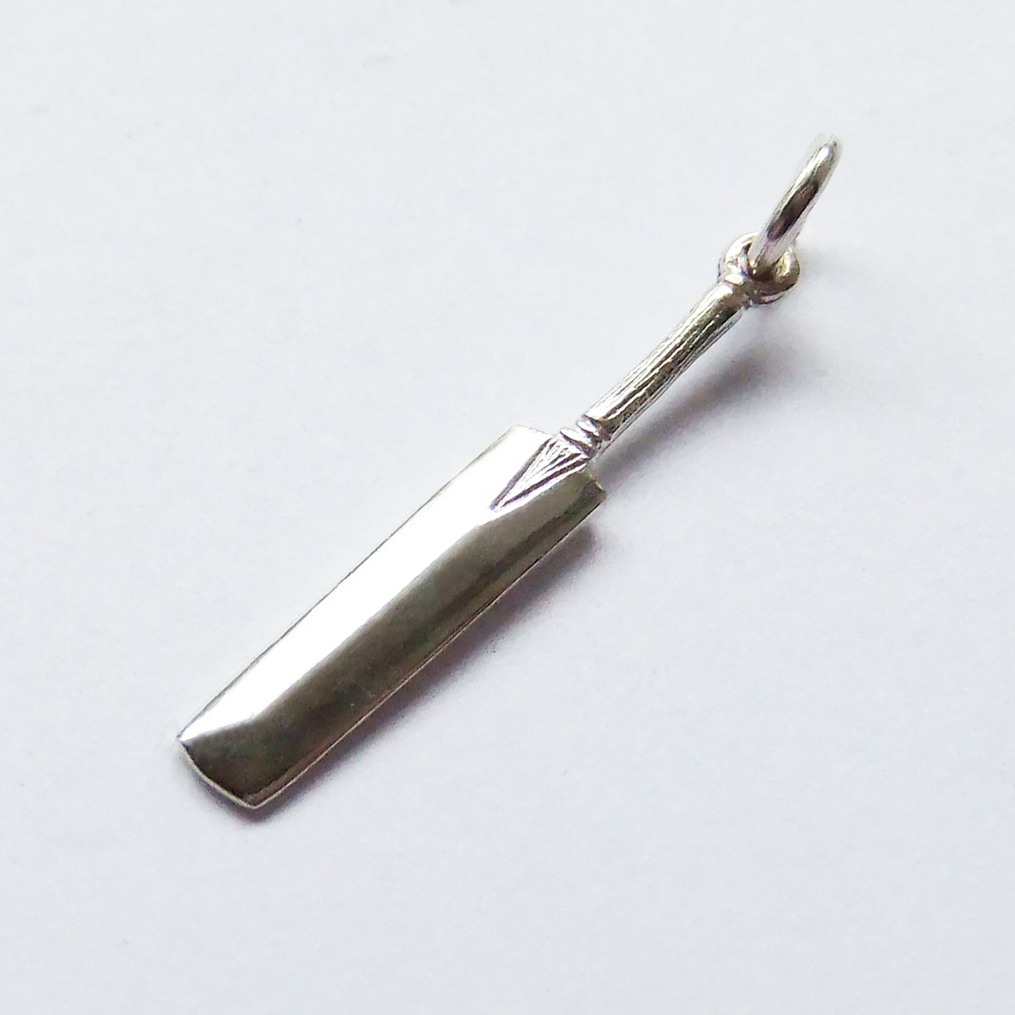 Sterling silver cricket bat charm on a grey background