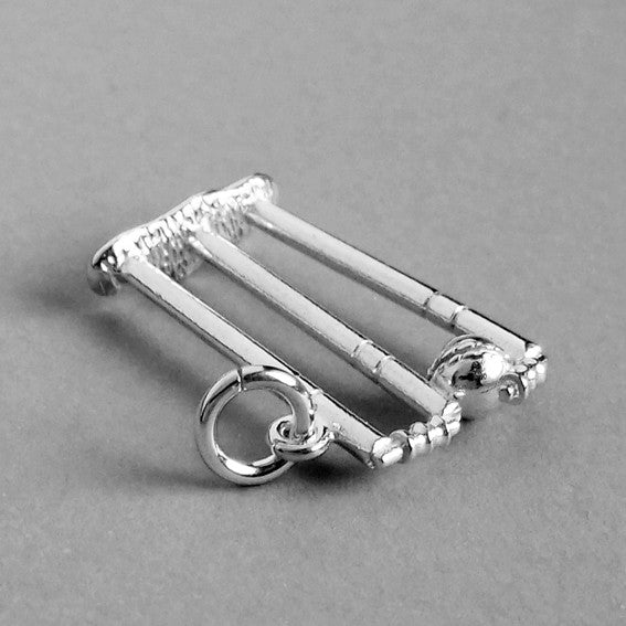 Sterling silver cricket stumps charm viewed from side on a grey background