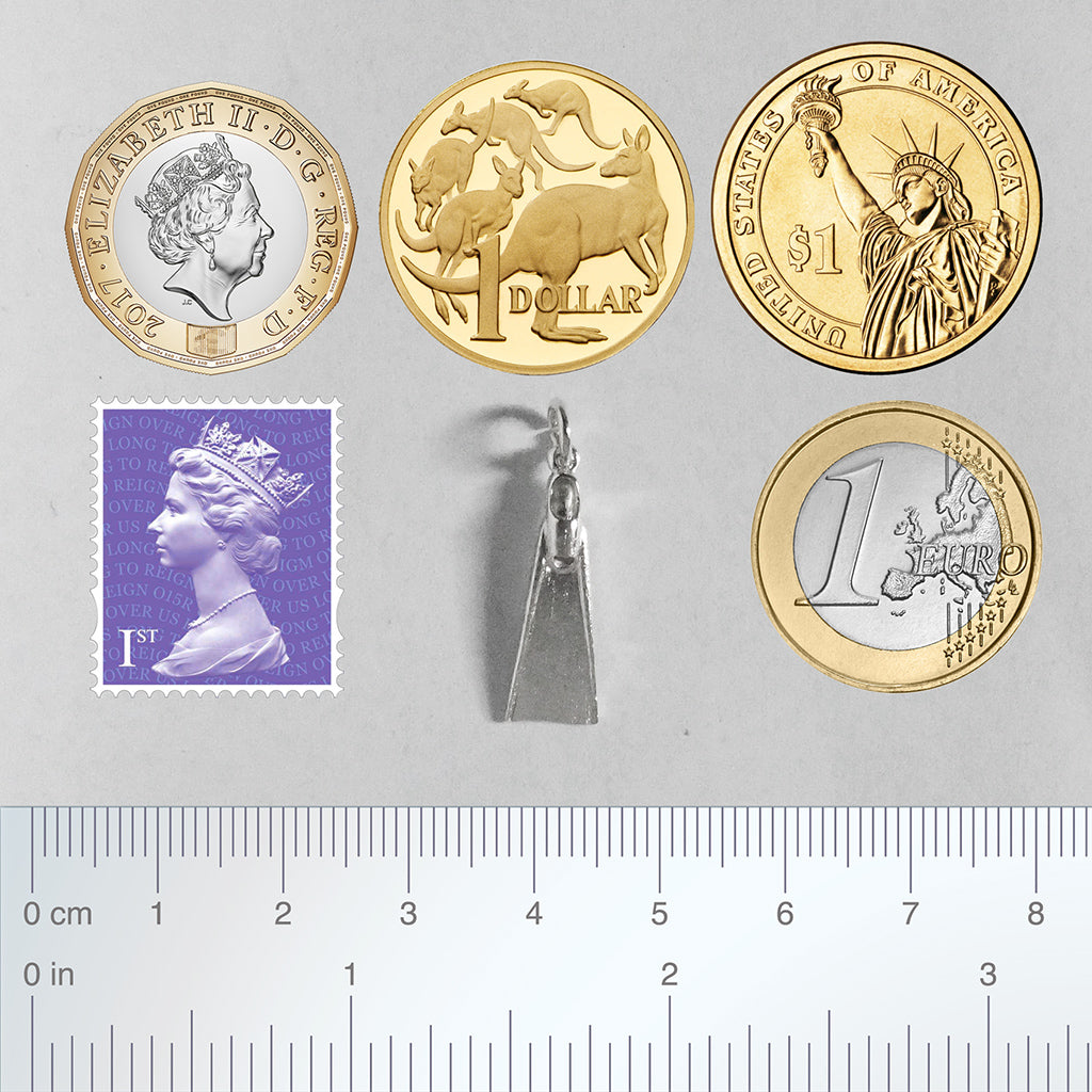 Sterling silver diving fin charm with coins stamp and ruler for scale on a grey background