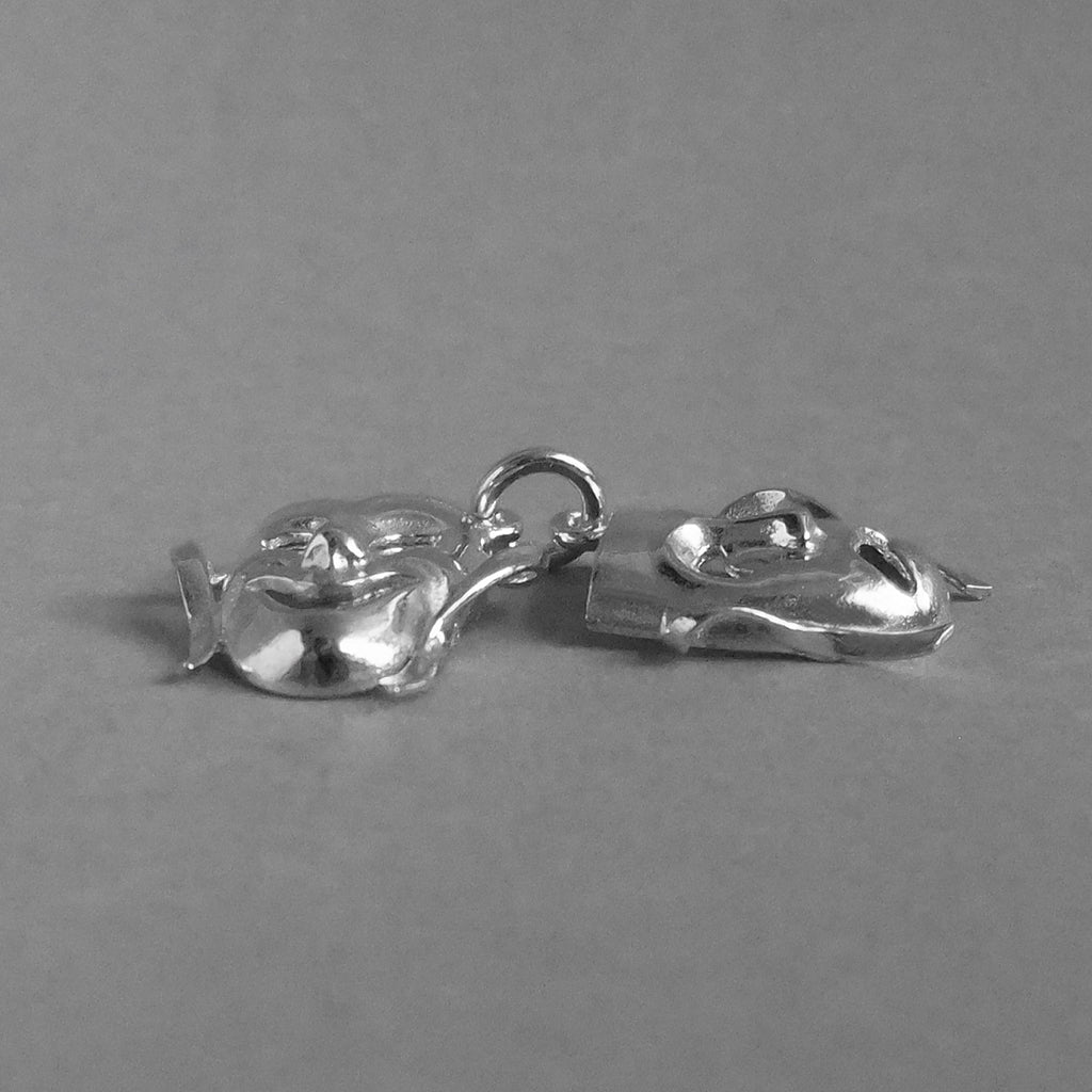 Sterling silver comedy and tragedy masks charm seen from side on a grey background