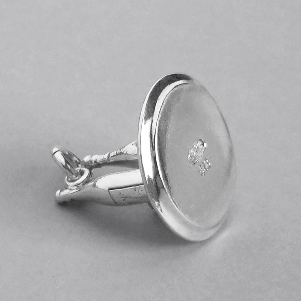 Underside of a sterling silver drinks tray charm on a grey background