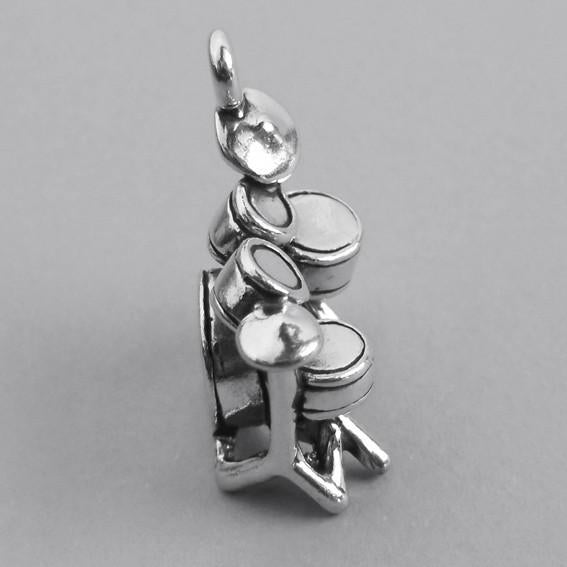 Sterling silver drum kit charm on a grey background