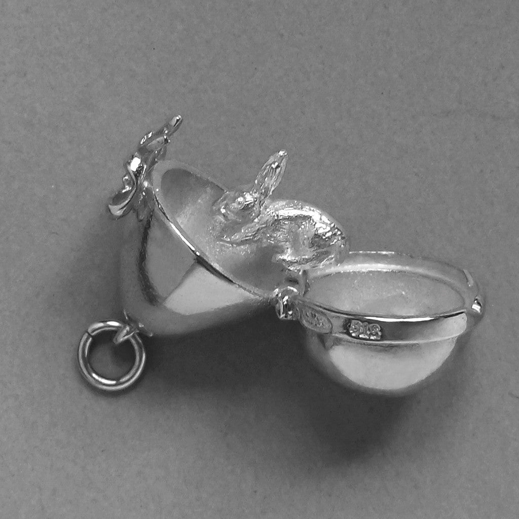 Sterling silver Easter egg charm with rabbit inside on a grey background