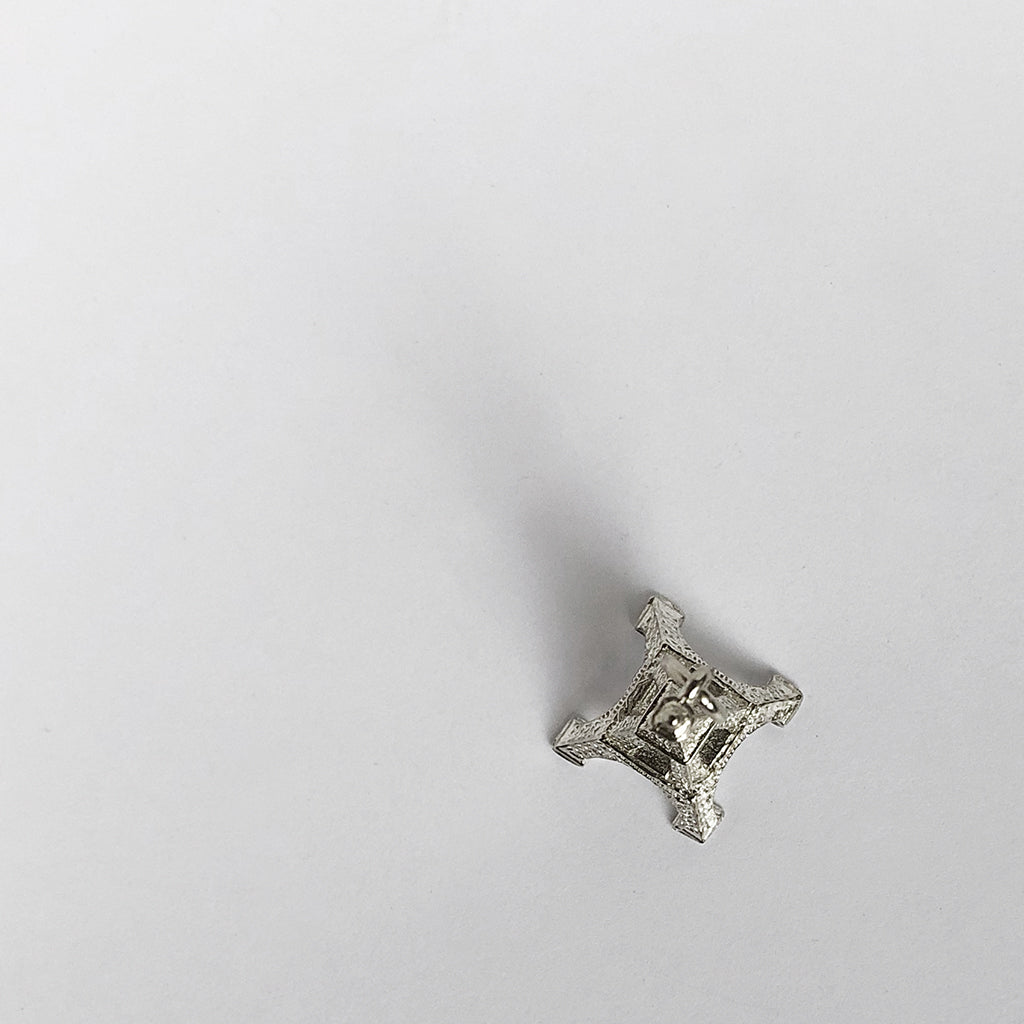Sterling silver Eiffel Tower charm viewed from above on a grey background