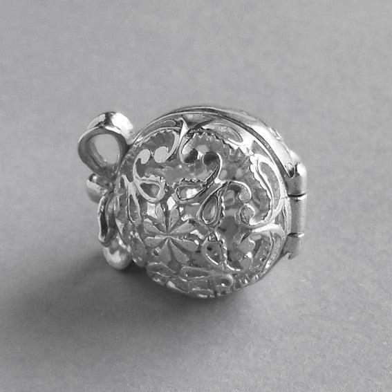 Base of a sterling silver filigree egg charm on a grey background