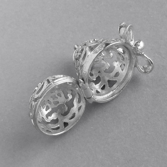 Sterling silver filigree egg charm on a grey background