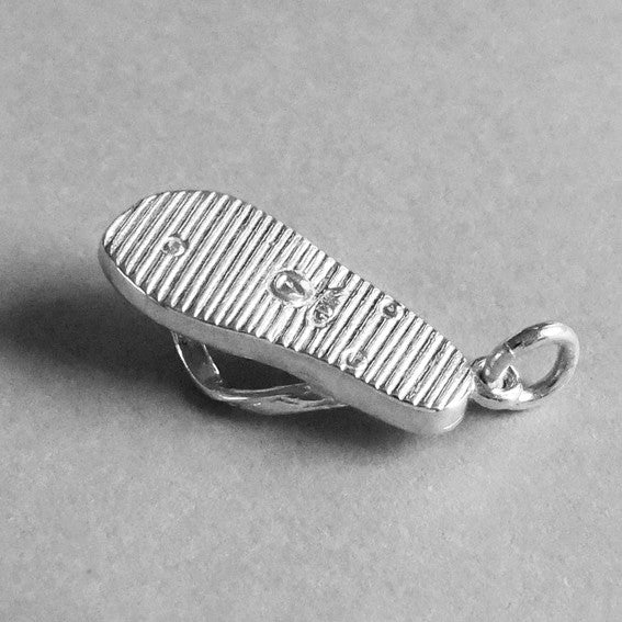 Underside of sterling silver flip flop charm on a grey background