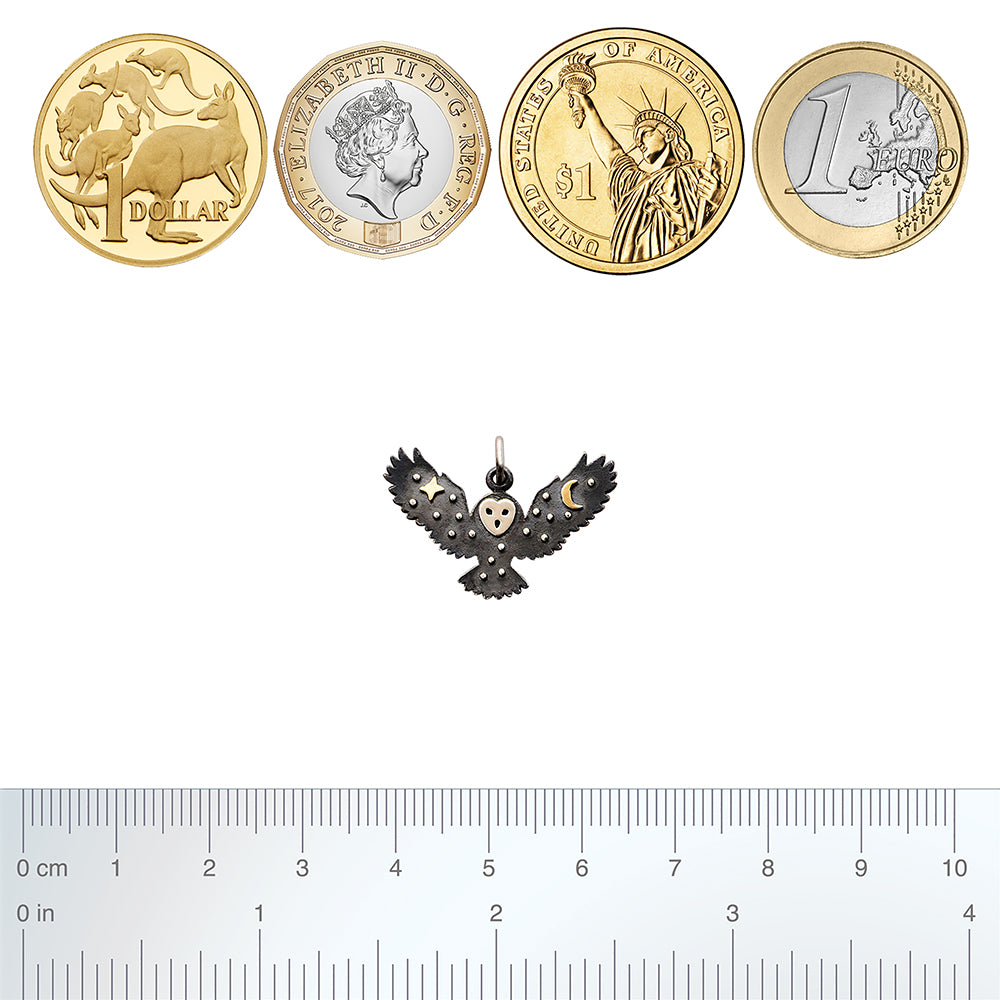 Sterling silver flying owl charm with bronze moon and star decoration with coins and ruler for scale on a white background