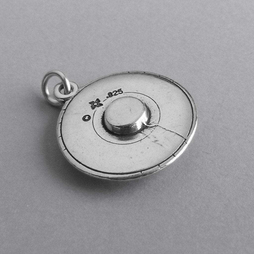 Reverse side of a sterling silver flying saucer charm on a grey background