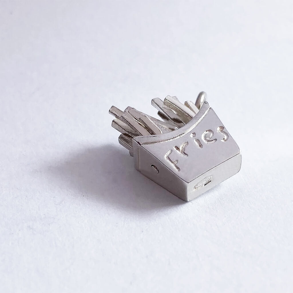Side view of a sterling silver French fries charm on a white background